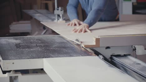 carpenter cutting a sheet of plywood with table saw