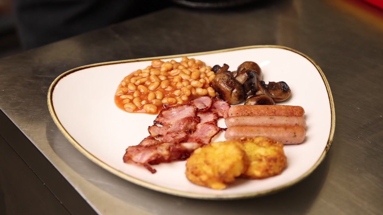 Klassisk komplett engelsk frukost med bacon, korv, bönor, svamp och hash browns