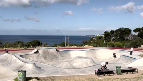 patinadores hábiles y experimentados divirtiéndose en la rampa de la piscina en un día soleado