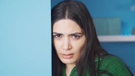 una joven deprimida y asustada mirando a la cámara en casa.