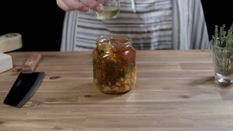 chef adds oil to a glass container to prepare chimichurri sauce, the perfect sauce for argentine barbecues