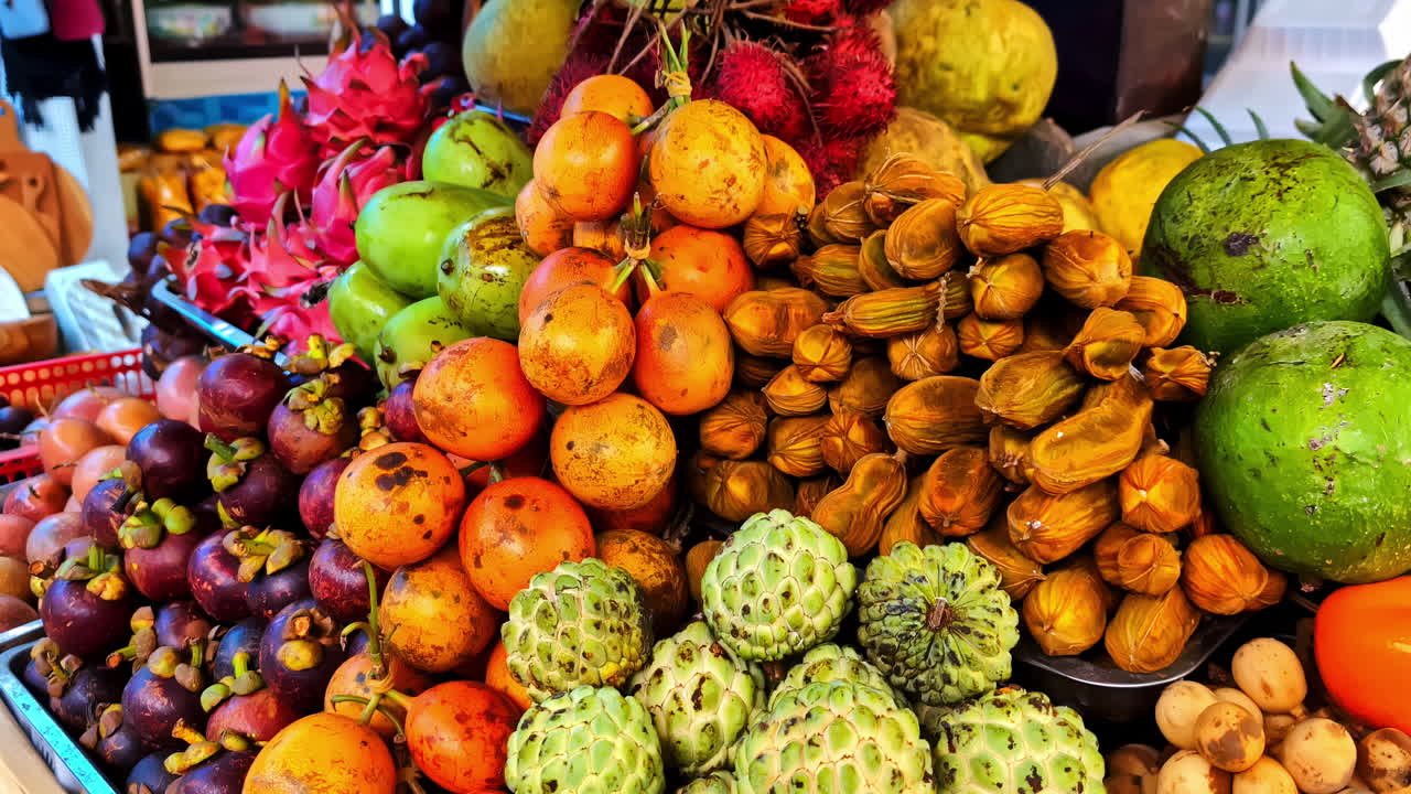 A vibrant display of exotic tropical fruits, including dragon fruit, custard apple, mangosteen, and coconut, at the bustling Tirta Empul market near Ubud, Bali
