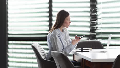 Young-Caucasian-businesswoman-in-a-striped-shirt-records-a-voice-message-on-her-phone