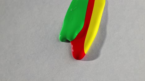 three colorful droplets of paint draining slowly