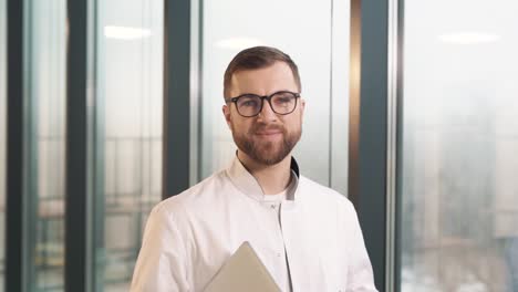 close-up of a male doctor walking past the large panoramic windows of a modern clinic