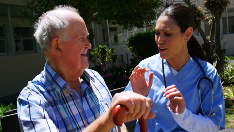 Vista-Frontal-De-Un-Hombre-Mayor-Caucásico-Activo-Y-Una-Doctora-Interactuando-Entre-Sí-En-El-Jardín