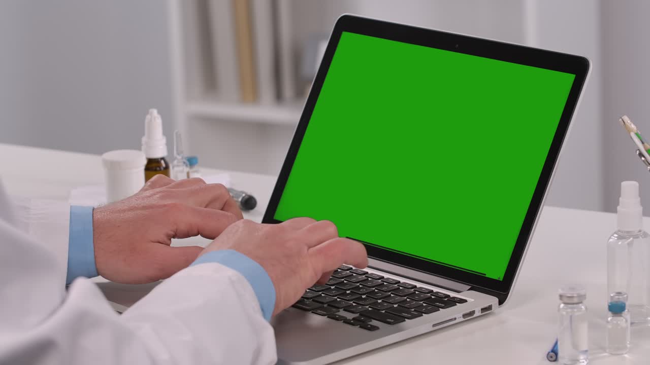 el médico masculino utiliza una computadora portátil con una tecla de croma de pantalla verde para trabajar y escribir. telemedicina, concepto de telesaúde. consulta remota de pacientes, distanciamiento social. acercamiento. cámara lenta
