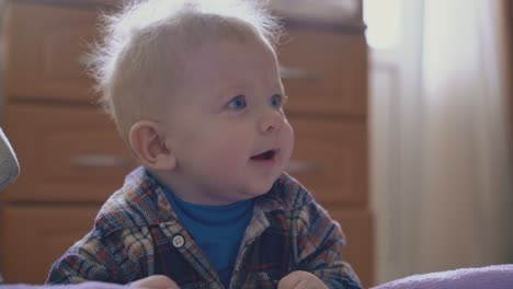 happy-boy-with-blond-hair-plays-with-thin-tube-at-large-bed