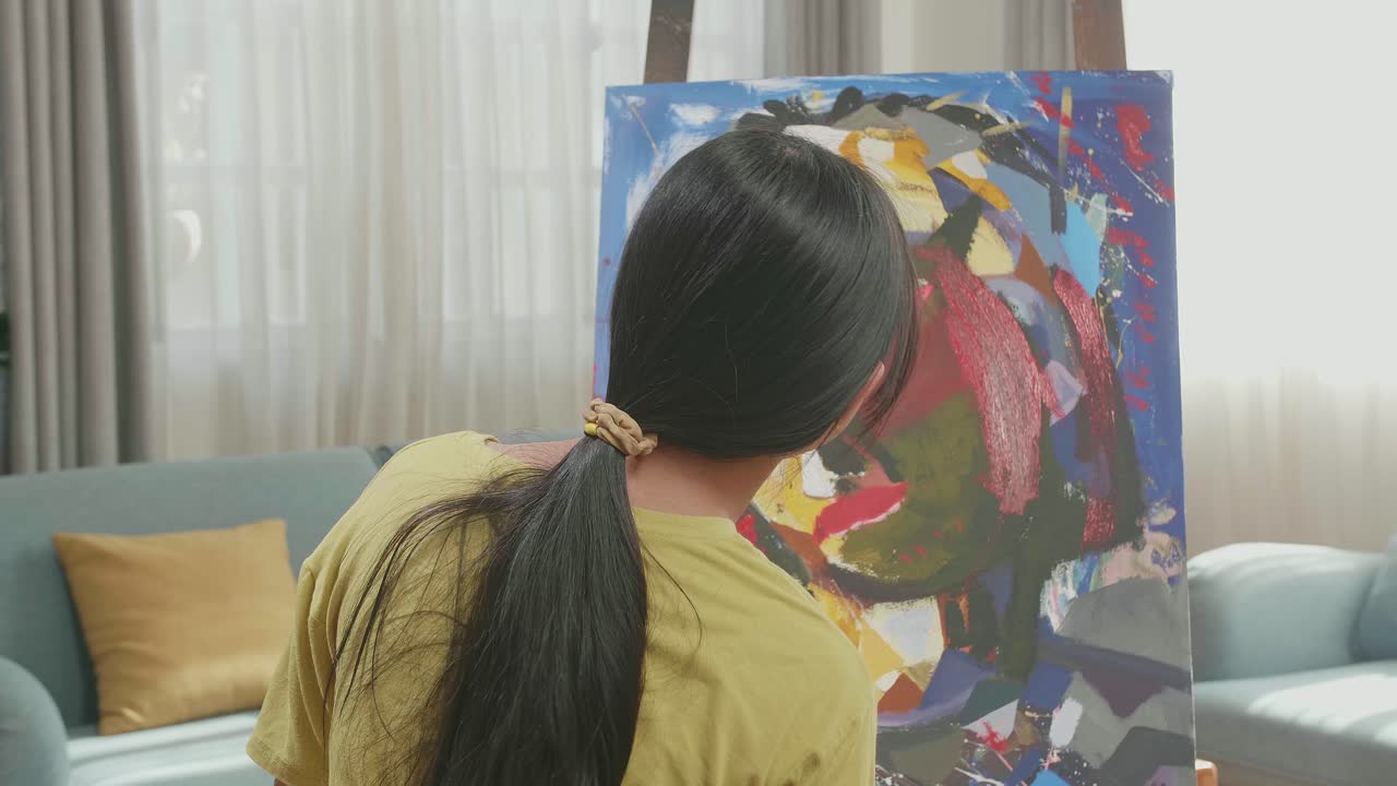 Hind View Of Asian Artist Girl Holding Paintbrush Mixed Colour And Thinking Before Painting A Girl'S On The Canvas