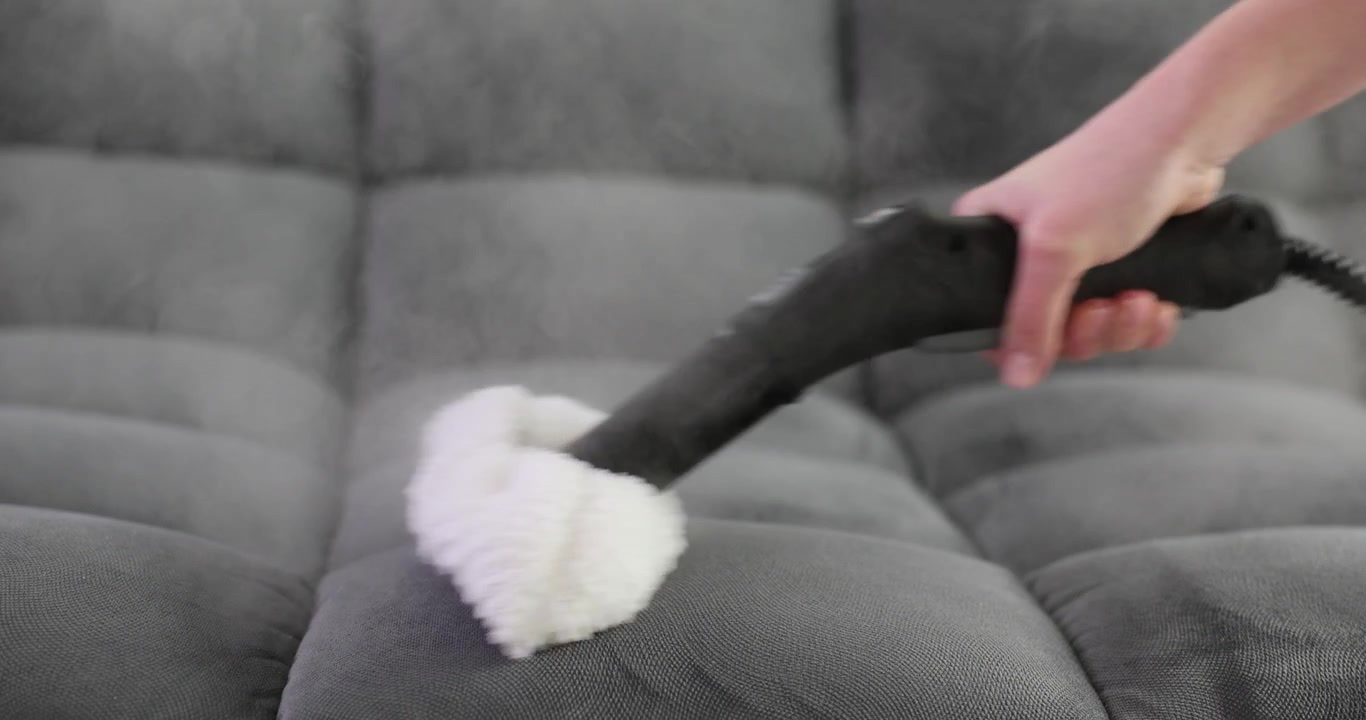 Dona de casa limpa sofá grande usando limpador a vapor de alta potência