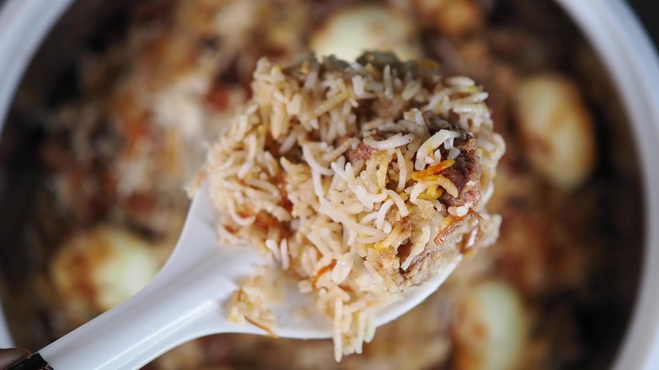 Primer plano de una cucharada de biryani de pollo recién cocinado