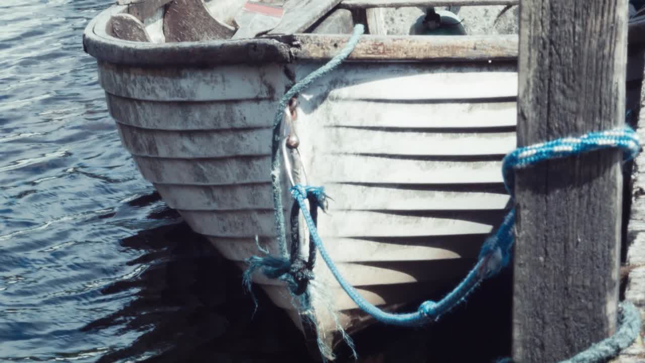 Handheld shot bow of fiberglass and wooden lake boat moored up to wooden jetty