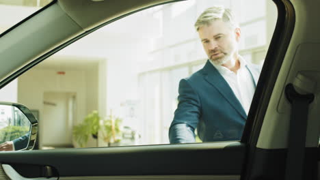 businessman entering car at dealership