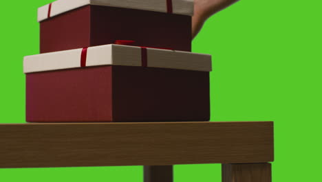 Nahaufnahme-Eines-Mannes,-Der-Verpackte-Geschenke-In-Schachteln-Vom-Tisch-Aufhebt,-Aufgenommen-Vor-Einem-Greenscreen