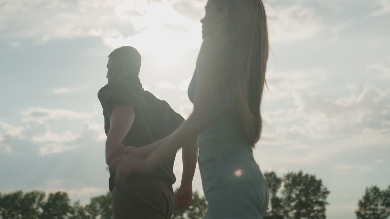 side view couple running through sunlit green field, woman long hair swaying in breeze with tired gasps, man powering stride, sun flare accentuating