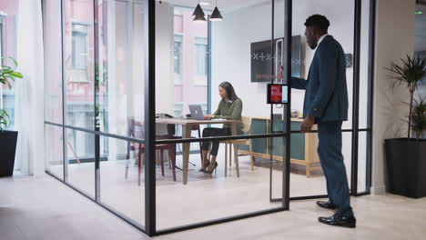 businesswoman shaking hands with male candidate in meeting room as he arrives for job interview