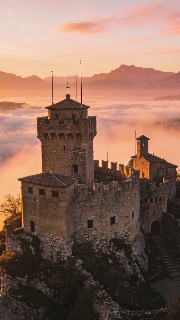 Video verticale: Telecamera aerea in avvicinamento con panoramica a destra verso un castello in cima a una scogliera, rivelando i merli.