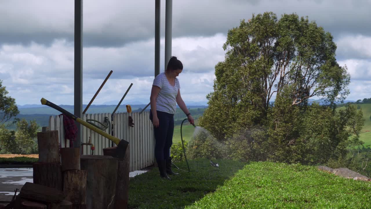 Lady watering newly laid turf with garden hose