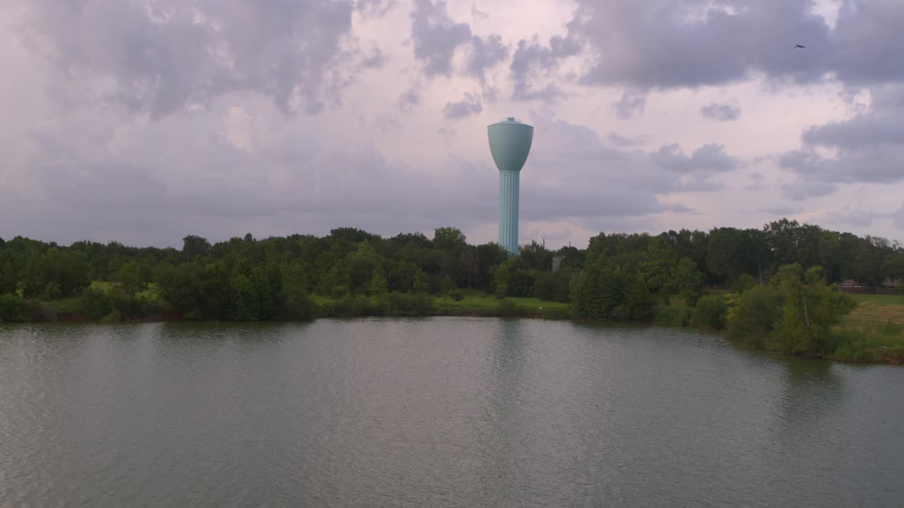Wide angle shot of Brays Bayou and large light blue water tower in Alief area in Houston