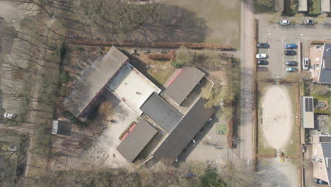 Top-down-aerial-of-children-playing-on-grade-school-playground---drone-setting-down