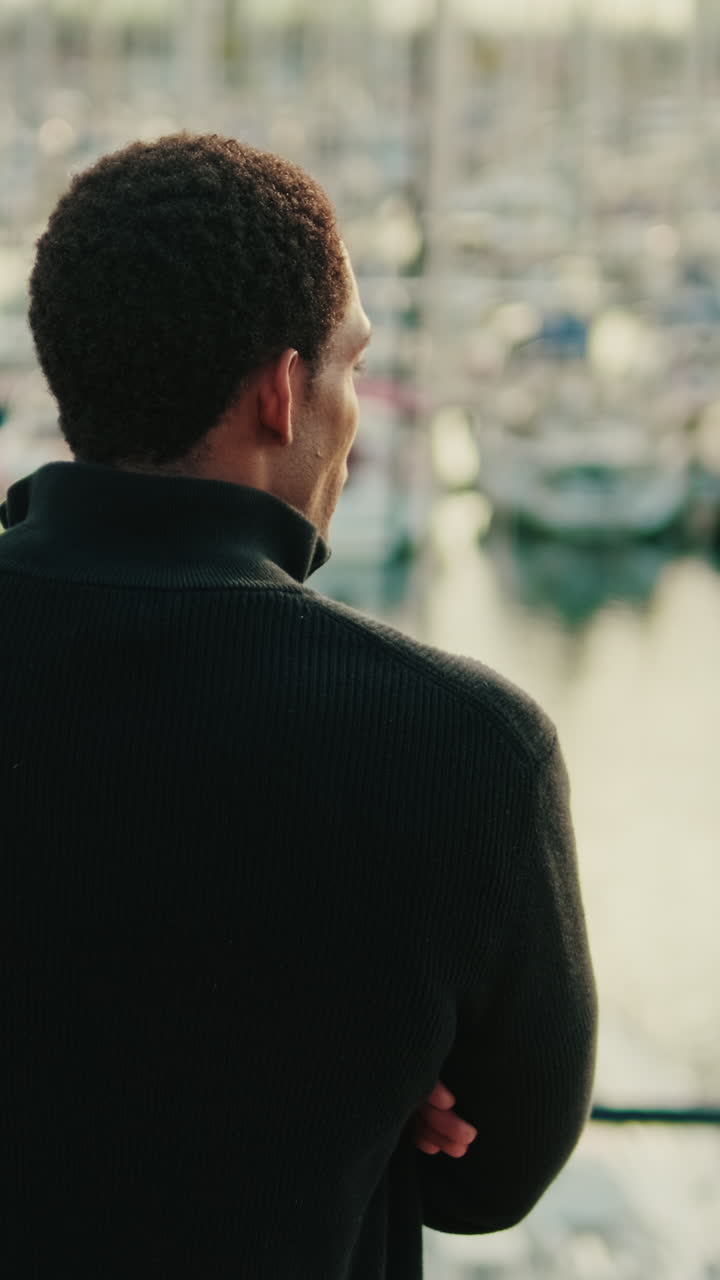 Young Man Looking Out at Boats in a Marina