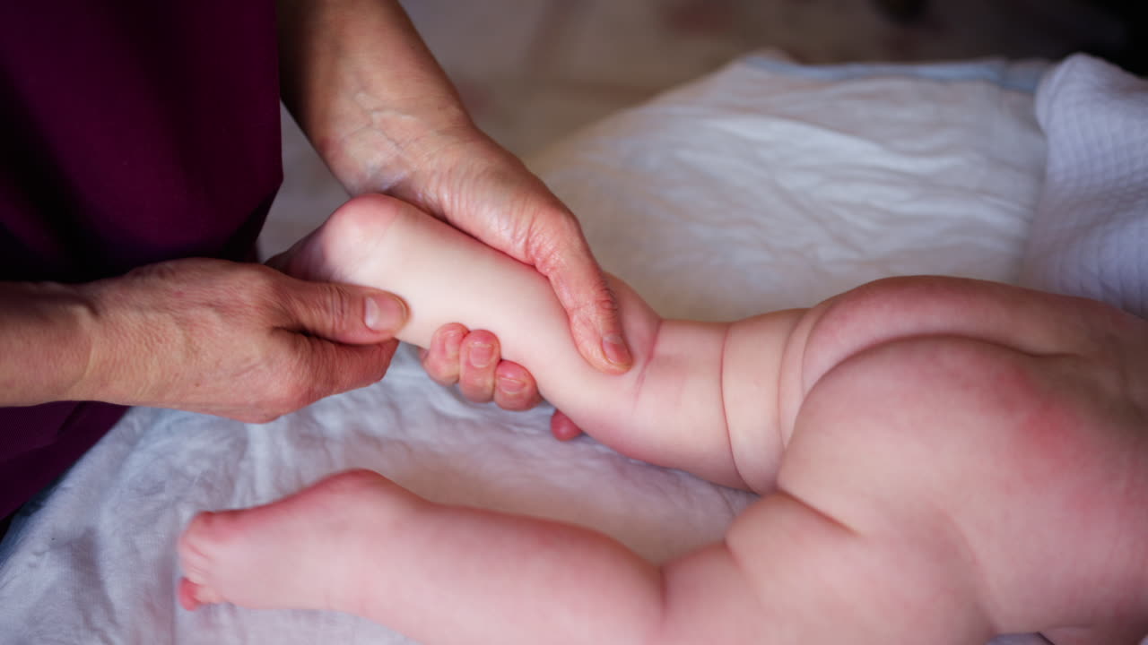 Bambino sdraiato sulla pancia mentre un adulto lo massaggia ed esegue esercizi di mobilità