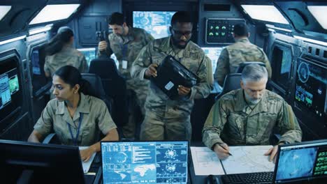 in a modern control room, military personnel engage in strategic planning and communication, utilizing advanced technology.