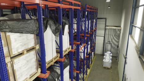 inside a warehouse: many shelves laden with neatly stacked pallets, anonymous containers