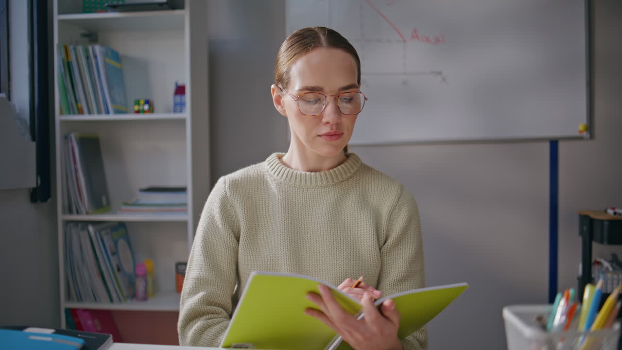 Smart woman checking test at school class closeup. Teacher in glasses working