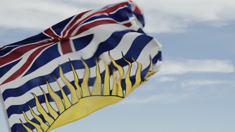la bandera de la columbia británica ondeando en el viento, contra un cielo azul