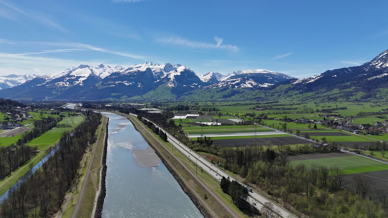 el tráfico en la carretera, los campos agrícolas y el río rin entre suiza y el país de liechtenstein;