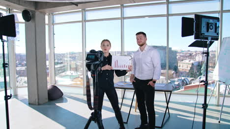 young business people talking about new strategy. attractive female holding graphics of business project and speaking on camera in office room.