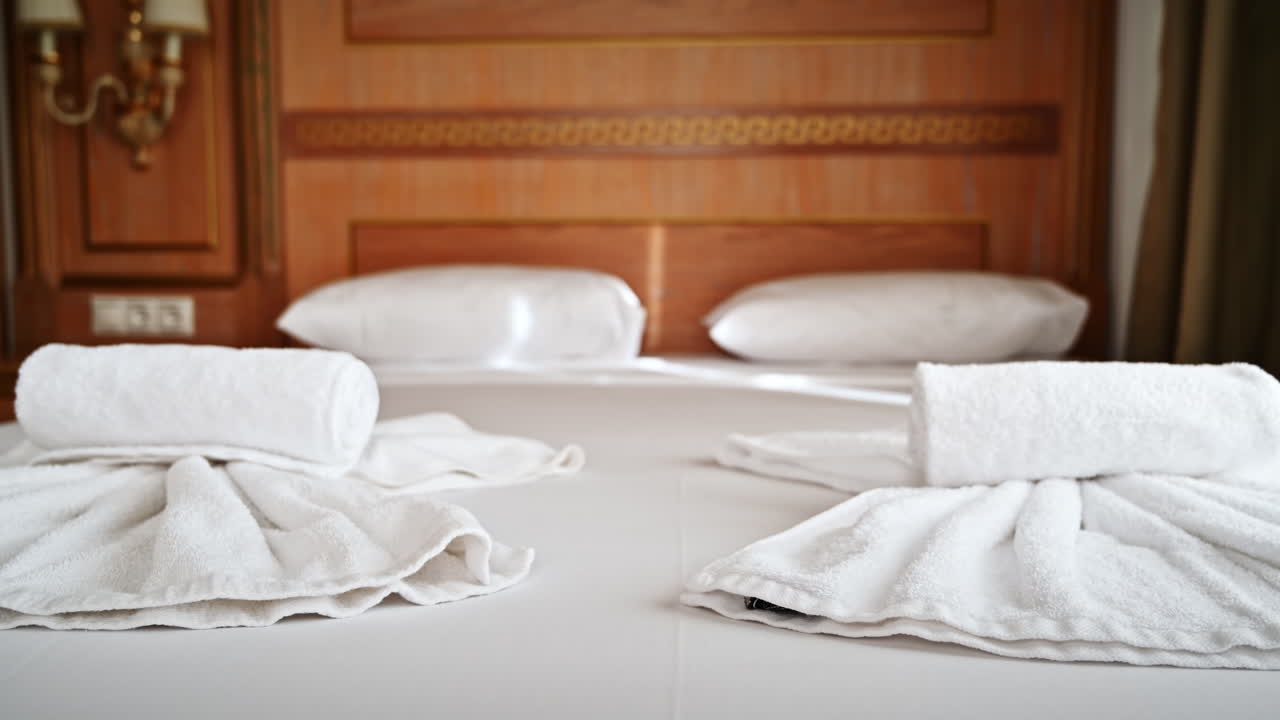 Bed with pillows and towels in the bedroom in a hotel with wooden finish in Greece
