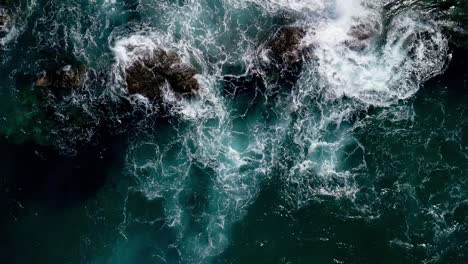 vista aérea sobre las olas del océano que se estrellan sobre las rocas en cámara lenta, vista de arriba hacia abajo en cámara lenta