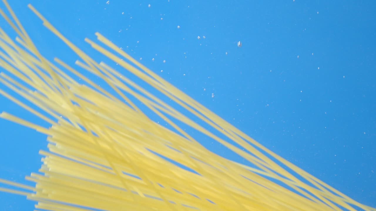 건조한 파스타 스파게티는 공기 거품으로 천천히 물 아래로 떨어집니다.