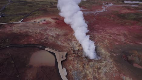 Tourist-man-walking-along-footpath-next-to-the-steam-vent-at-Gunnuhver,-Iceland