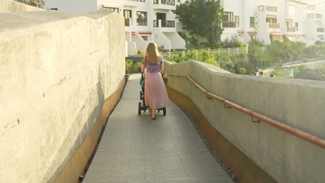 Happy-mother-pushing-stroller-on-warm-day-in-Tenerife-island-cityscape