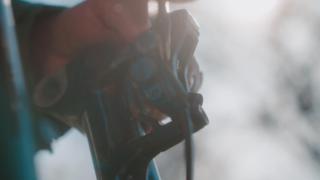 Close-up of a hand using pliers to adjust a mechanical part outdoors in soft lighting