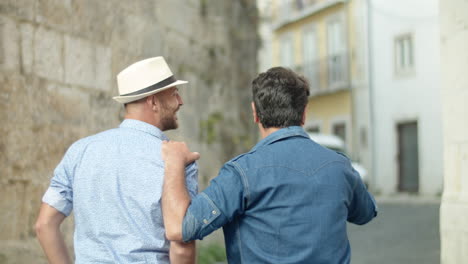 back view of guy walking and putting hand on boyfriends shoulder