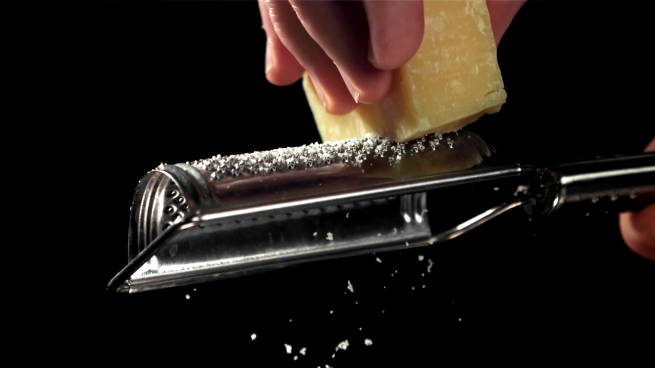 Grattugiatura al rallentatore di Parmigiano su sfondo nero