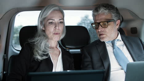 woman and man working with laptops in car