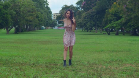 A-young-woman-walks-in-a-park-in-a-mini-dress-and-boots-in-a-Caribbean-city