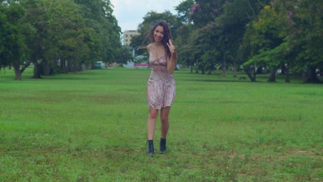 una mujer joven camina en un parque con un mini vestido y botas en una ciudad caribeña