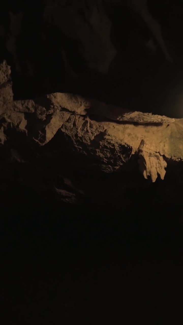 Moving Through a Dark Cave with Water and Illuminated Rock Formations