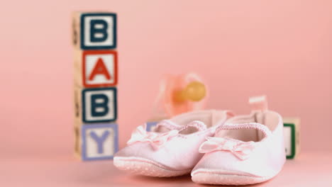 baby shoes falling in front of baby blocks and soother