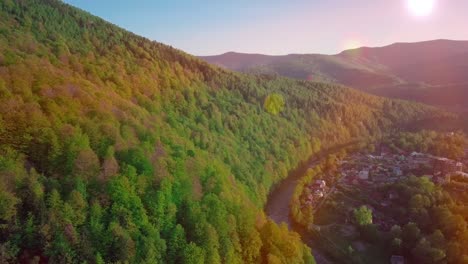 aerial drone footage view: flight over spring mountain village with forest in sunrise soft light. image processed in orange glow. carpathian mountains, ukraine, europe. majestic landscape. beauty