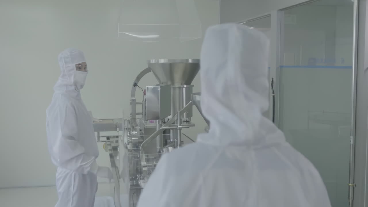 Scientist or factory workers wearing sterile gloves inspects medical vials on a production line conveyor belt at a pharmaceutical manufacturing plant