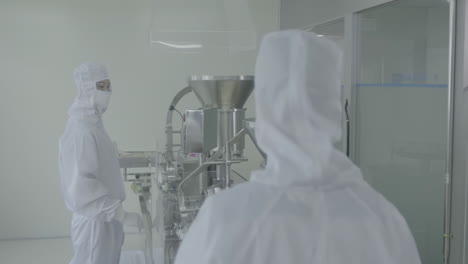 scientist or factory workers wearing sterile gloves inspects medical vials on a production line conveyor belt at a pharmaceutical manufacturing plant