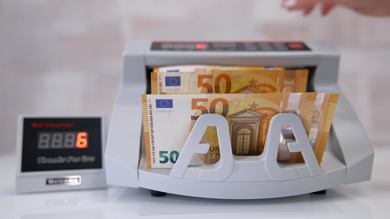 Electronic device is calculating fifty-euro bills. Woman puts paper banknotes into automatic counting machine. Automatic mechanism for bank financial operations. Currency exchange.
