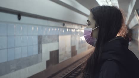 woman wearing a mask waiting at a subway station